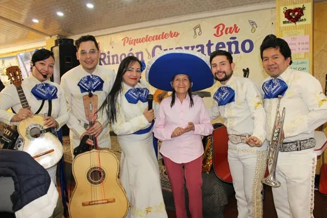 Mariachi con traje blanco en sorpresa para abuelita en piqueteadero Bogotá