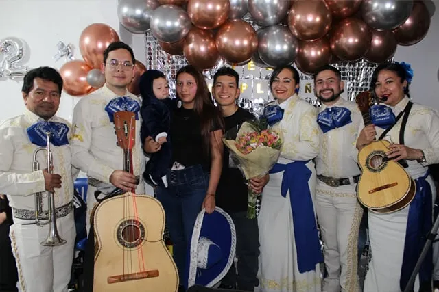 Mariachi con traje blanco en cumpleaños sorpresa de pareja joven con bebé Bogotá
