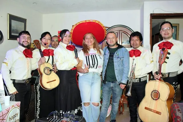Mariachi con traje blanco y negro en cumpleaños sorpresa de pareja en departamento Bogotá