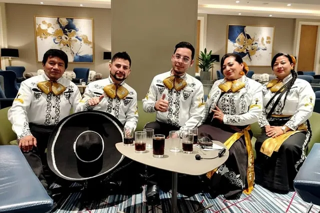 Mariachi con traje blanco y negro en sala de hotel elegante tomando bebida Bogotá
