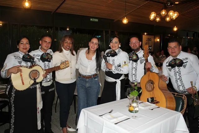 Mariachi con traje blanco y negro en celebración de compañeras de trabajo en restaurante Bogotá