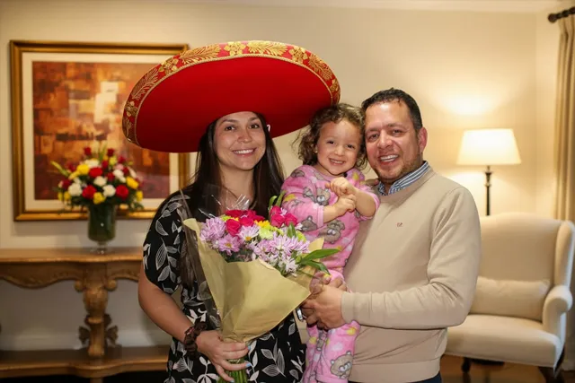Esposa con esposo e hija después de serenata sorpresa con sombrero y flores Bogotá